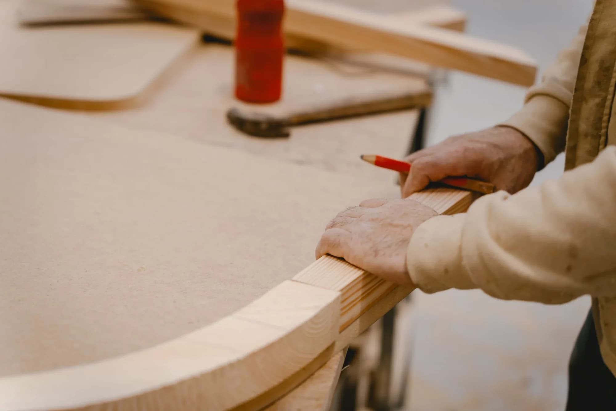 An ELBRA craftsperson holding a pencil against the edge of a curved timber frame