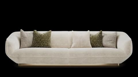 Curved cream sofa with rounded arms and five scatter cushions on a recessed brass plinth